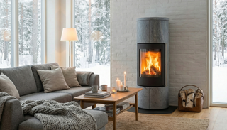 Stor täljstenskamin med sprakande eld i ett mysigt vardagsrum